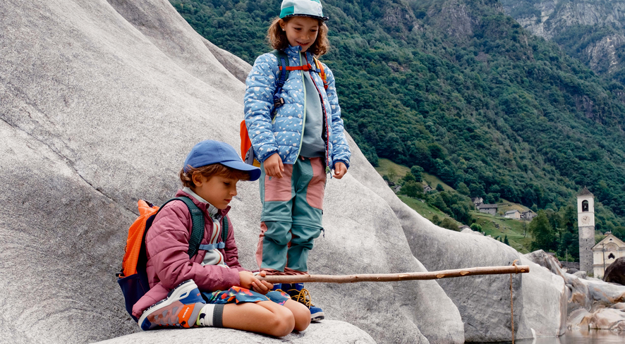 Two children are playing with a homemade fishing rod in the Verzasca Valley.
