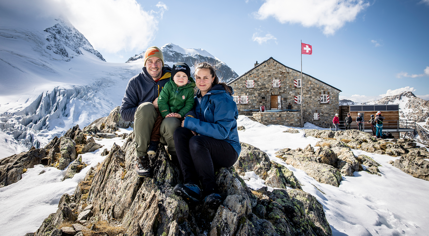Family sitting on a rock in front of the Tierbergli hut