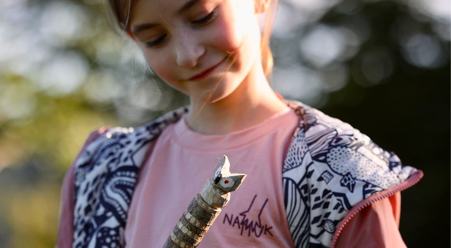 Girl in namuk clothing showing her self-carved walking stick