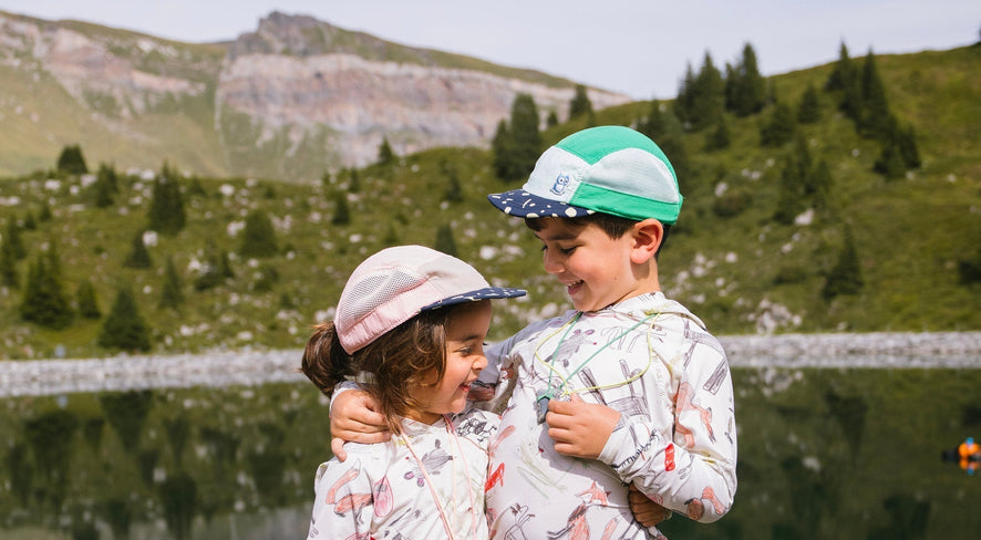 Two kids standing in front of a lake in the mountains