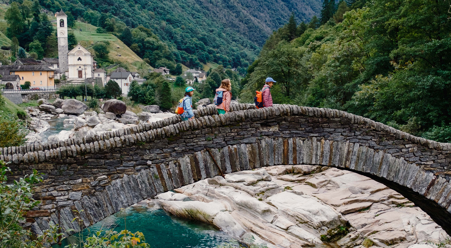 Children running across the Roman bridge in the Verzascatal.