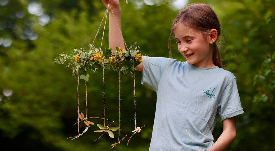 child with a dragonfly mobile made from natural material