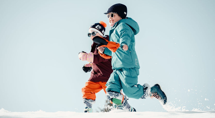 Kids in namuk ski gear running in the snow